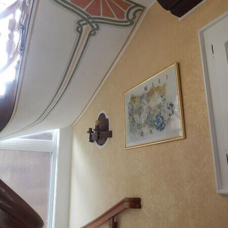 Treppenaufgang mit floraler Deckenbemalung und antiker Wandlampe