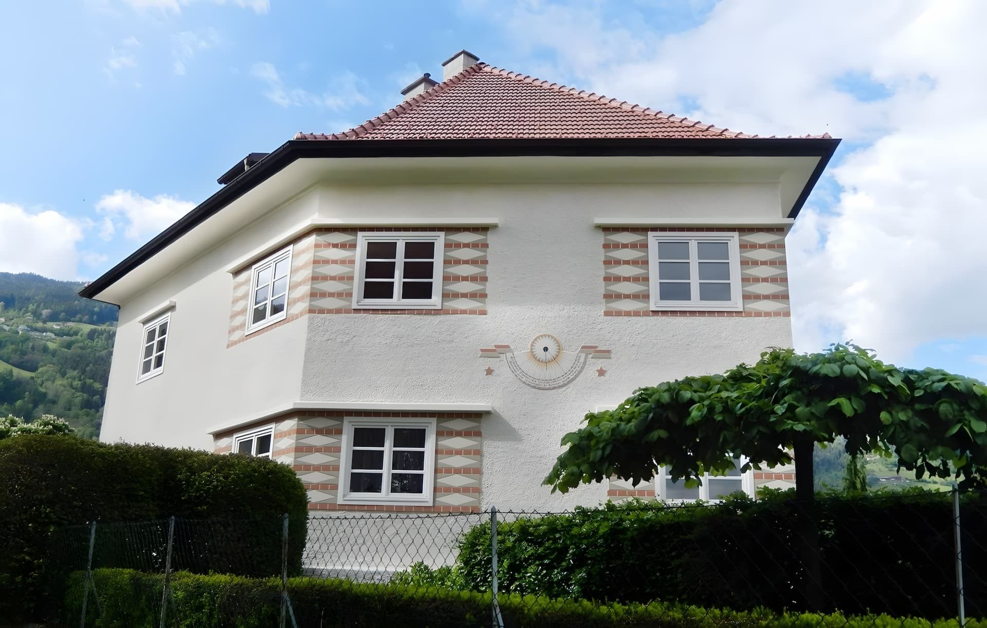 Haus mit Sonnenuhr und verputzter Fassade